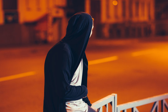 Young Happy Handsome Casual Student In Hood Outdoors. Portrait Of Hooded Guy Walking Through Night City