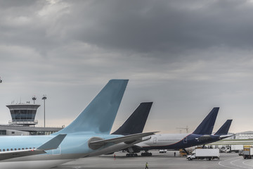 Tails of some airplanes at airport during boarding operations. They are four planes on a sunny day, with a blue sky. Travel and transportation concepts