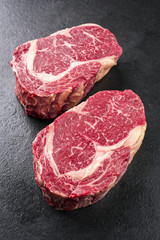 Two raw dry aged Kobe Entrecote Steak as close-up on a slate