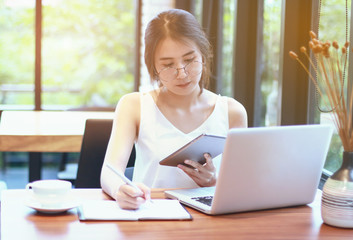 businesswoman smiling and thinking in front of laptop while sitting at co-working space office to manage her coffee shop.Small business pondering over ideas for new business project,vintage tone