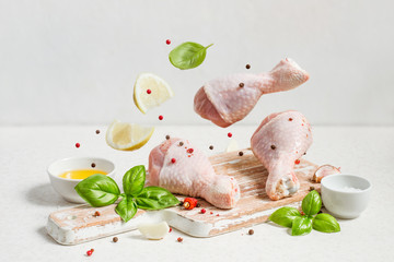 Raw chicken drumstick And spices fly over the cutting board, copy space