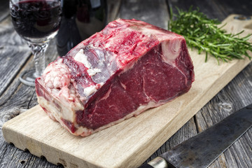 Raw dry aged Rib of Beef as close-up on an old cutting board
