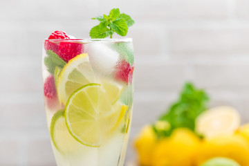 Lemon mojito cocktail with lime, mint and raspberry, cold drink with ice.