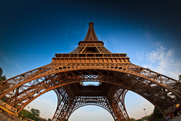 A low angle fisheye shot of the Eiffel Tower in Paris, France, against a clean blue sky