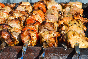 Grilled kebab cooking on metal skewer closeup. Roasted meat cooked at barbecue. Traditional eastern dish, shish kebab. Grill on charcoal and flame, picnic