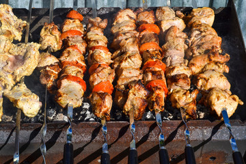 Grilled kebab cooking on metal skewer closeup. Roasted meat cooked at barbecue. Traditional eastern dish, shish kebab. Grill on charcoal and flame, picnic