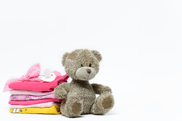 Set of baby clothes for girls, rattle, pacifier and Teddy bear on a white background. Space for text.