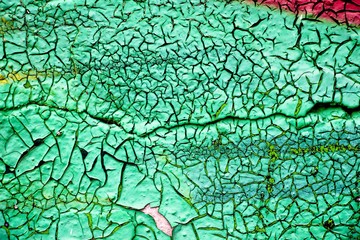 The old wall is painted with green paint, which from time to time has dried up and cracked.