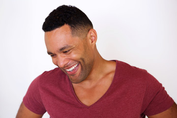 happy african american man looking down and smiling against white background © mimagephotos