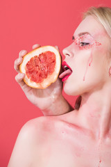woman with creative fashionable makeup lick grapefruit, vitamin