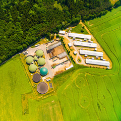 Aerial view over biogas plant and farm in green fields. Renewable energy from biomass. Modern...