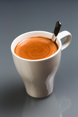 Tasse heiße Schokolade mit Löffel auf grauem Hintergrund, close-up