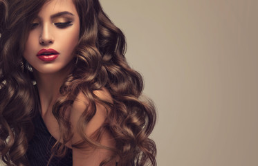 Brunettemädchen mit dem langen und glänzenden gewellten Haar. Schönes Modell mit lockiger Frisur.