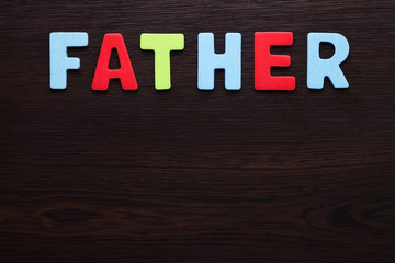 Father colorful letters on dark brown background.