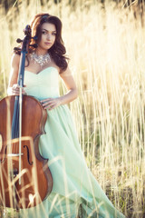 Girl with a cello in a tall grass