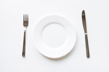 Empty white plate with fork and knife