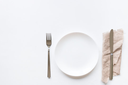 Empty plate on a white background and cutlery on a napkin mockup