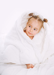 Fototapeta na wymiar Little child lying on bed at home. 2 years old baby rests on white blanket.