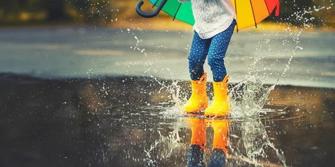 Foto op Canvas Feet of  child in yellow rubber boots jumping over  puddle in rain © JenkoAtaman
