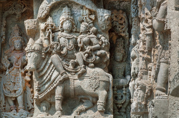 Fototapeta na wymiar Shiva, Parvati and bull Nandi on wall of Indian temple. Example of ancient architecture, 12th century decoration inside the Hindu temple Hoysaleshwara in Halebidu, India.