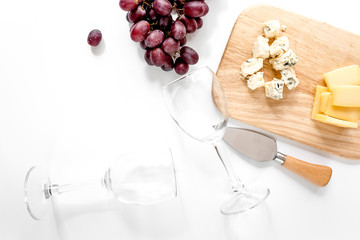 Bottle of red wine and wine glasses with cheese and grape aperitive on white background copyspace top view
