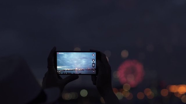 woman shoots fireworks on a mobile phone. hands of woman taking the photo to fireworks with the smartphone