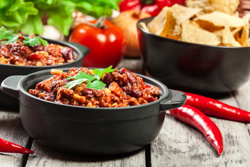 Bowls of hot chili con carne with ground beef, beans, tomatoes and corn