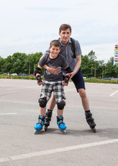 Caucasian young boy in roller-skating and father skating together on city streets