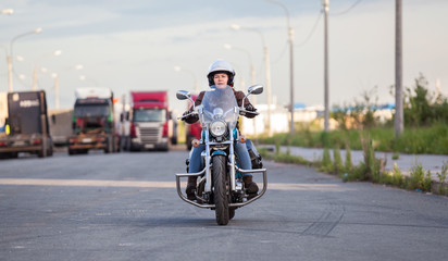 European female motorcyclist driving on chopper motorbike on asphalt highway, front view