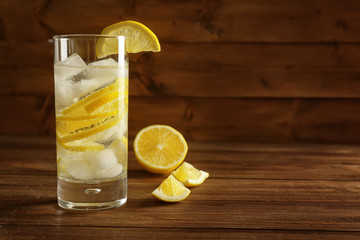 Glass of cold lemon water on wooden table