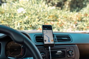Smartphone with navigation app on car dashboard.