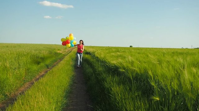 Girl with balloons in a field of wheat. Happy girl with balloons on nature.
