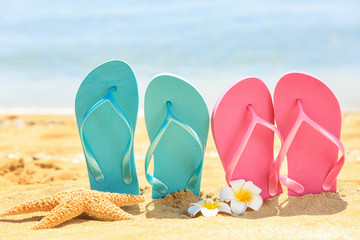 Colorful flip-flops and starfish on sand at sea shore. Vacation concept