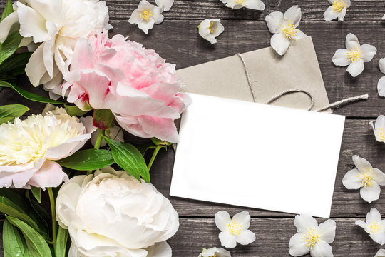 blank greeting card and envelope in frame of pink and white peonies and jasmine flowers