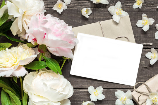 blank greeting card and envelope in frame of pink and white peonies and jasmine flowers