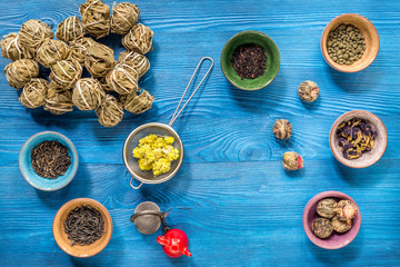 herbs in colorful bowls to make tea on blue table background top view