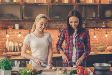Young women friends cooking meal together at home