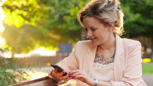 Attractive white woman blonde using a smartphone in park at sunny day