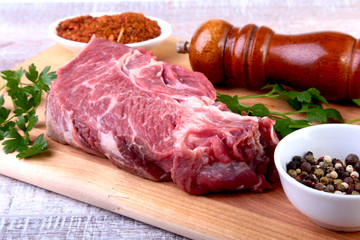 Raw beef steak with spices Leaves of coriander on wooden cutting board. Ready for cooking.