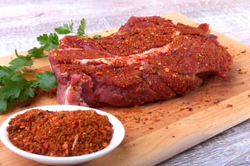 Raw beef steak with spices Leaves of coriander on wooden cutting board. Ready for cooking.