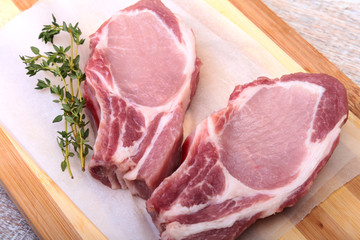 Raw pork chops, spices and rosemary on cutting board. Ready for cooking.