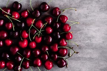 Deep dark cherries fruit pattern on gray concrete background. Copyspace. 