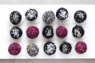 Various fitness bites, raw chocolate truffles, with rose petals, on white. Food photography from above, diet concept