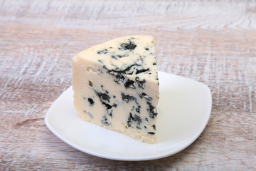 Plate with Tasty blue cheese on wooden table