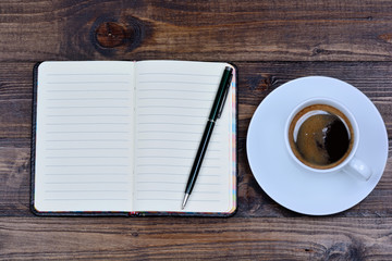 Notebook with pen and coffee on table
