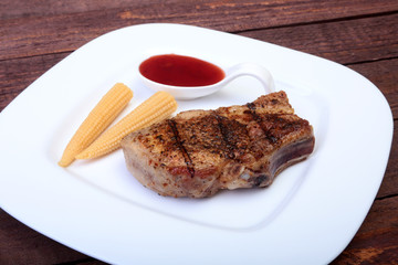 grilled pork chop with Cranberry sauce and Mini Corn cob preserved on plate on wooden board