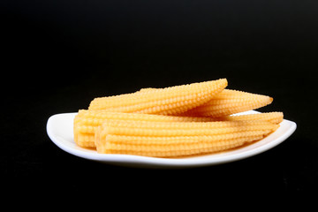 Mini Corn cob preserved on plate on wooden board.