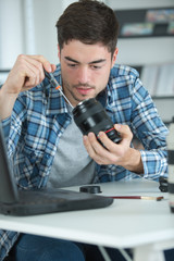 handsome technician examining and repairing dslr camera