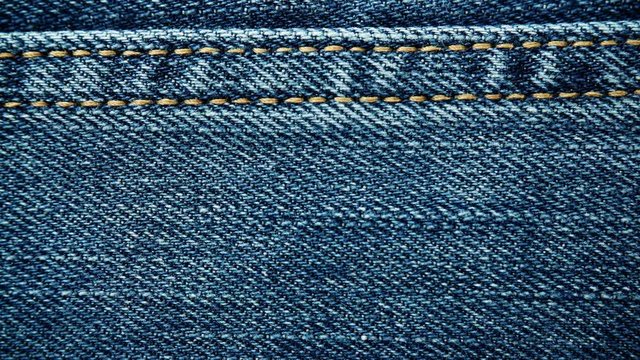 Closeup detail of blue denim jeans, texture background. Dolly sliding shot 4K ProRes HQ codec