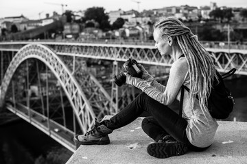 Young woman with dreadlocks, pictures of on camera, old city, Porto, Portugal. Black-and-white photo.